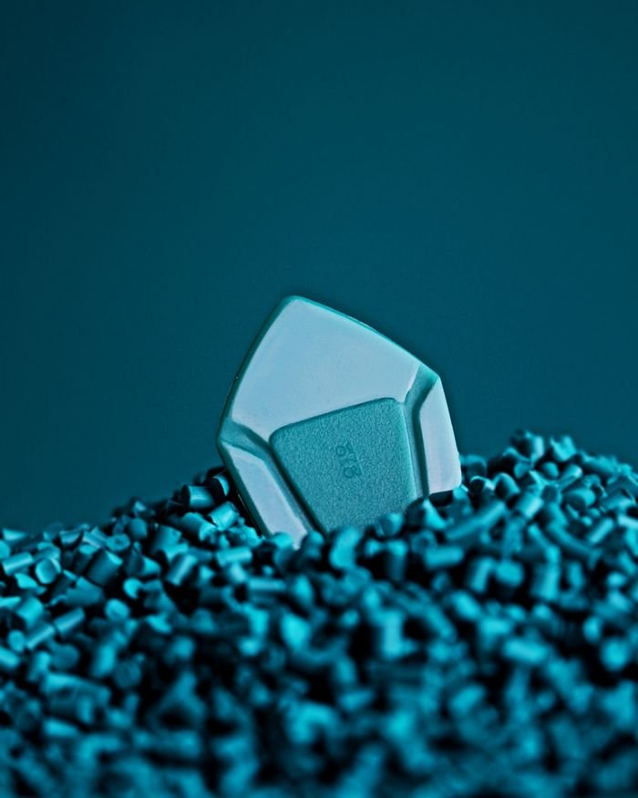 Detailed close-up of a guitar pick partially submerged in a textured blue surface, perfect for musicians.