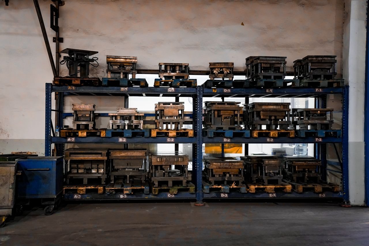 Metal molds neatly arranged on industrial shelving in a warehouse setting, showcasing order and efficiency.